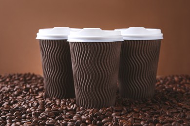 Photo of Coffee to go. Paper cups on roasted beans, closeup