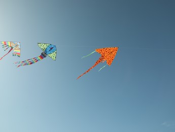 Photo of Bright rainbow kites in blue sky, low angle view