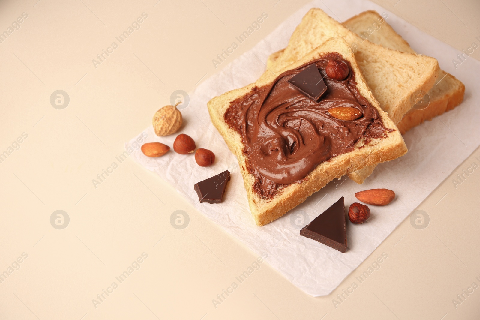 Photo of Tasty toast with chocolate paste and nuts on light background, space for text