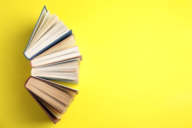 Photo of Hardcover books on yellow background, flat lay. Space for text