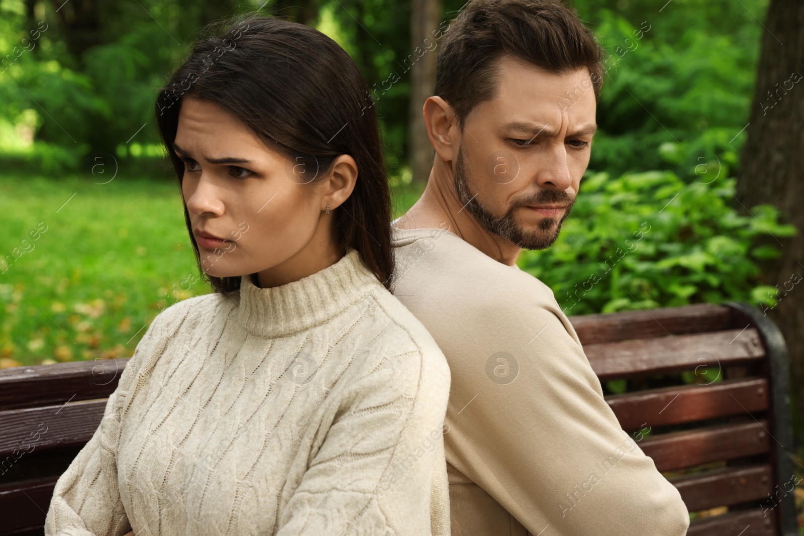 Photo of Upset arguing couple sitting on bench in park. Relationship problems