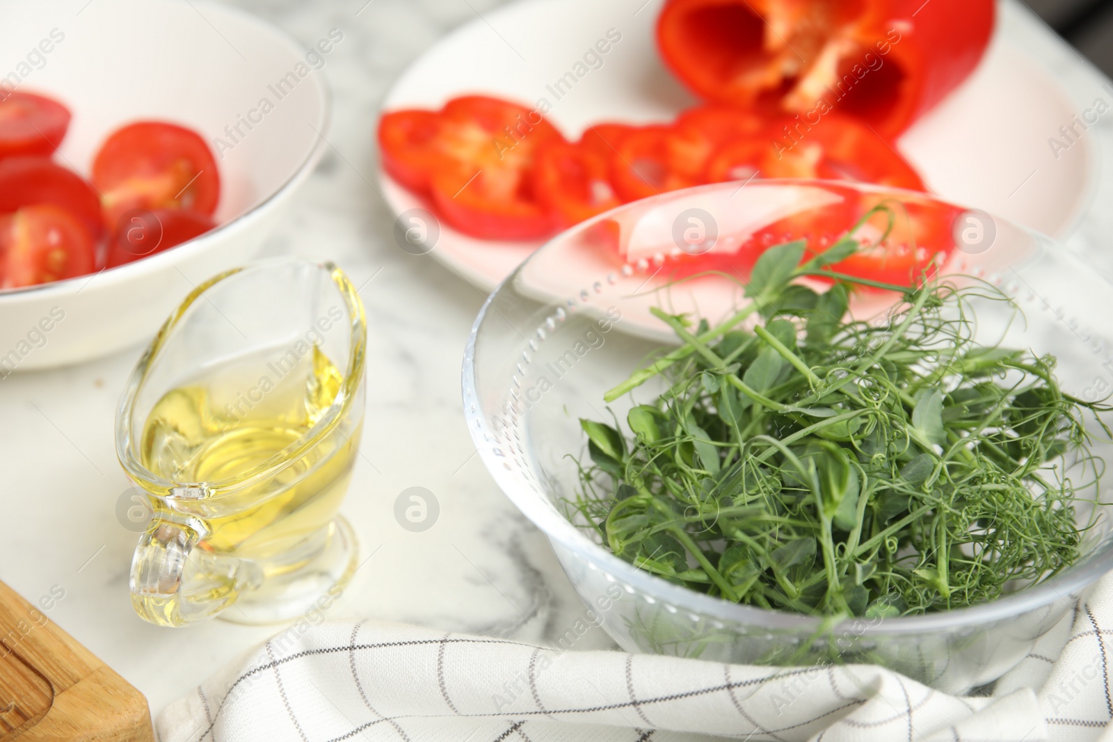 Photo of Fresh microgreens for tasty salad on white marble table, closeup