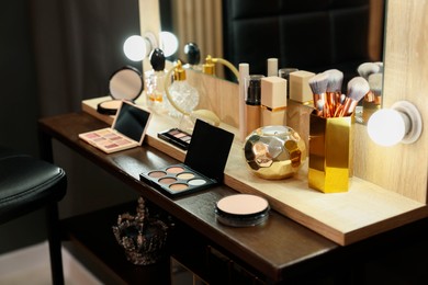 Makeup brushes and cosmetic products on dressing table in room