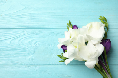 Photo of Bouquet of beautiful spring flowers on blue wooden table, top view