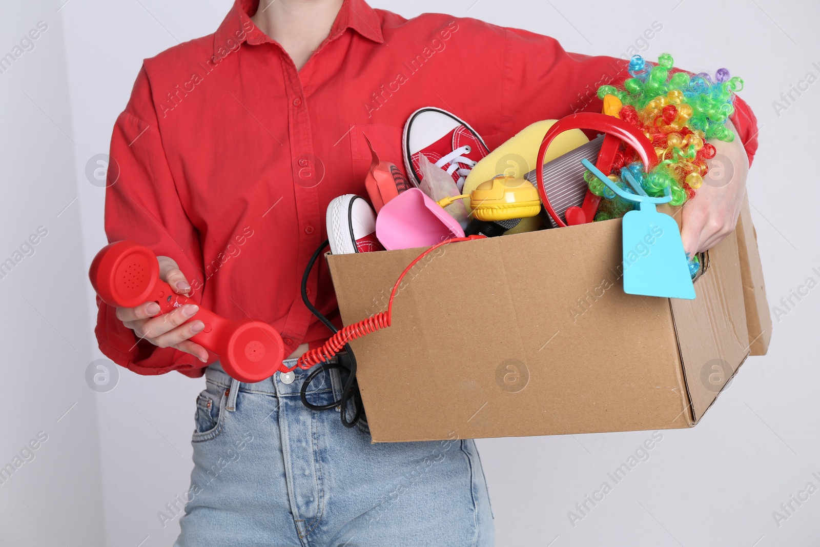 Photo of Woman holding box of unwanted stuff on white background, closeup