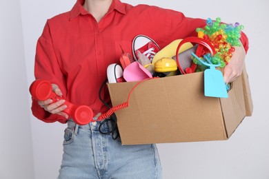Woman holding box of unwanted stuff on white background, closeup