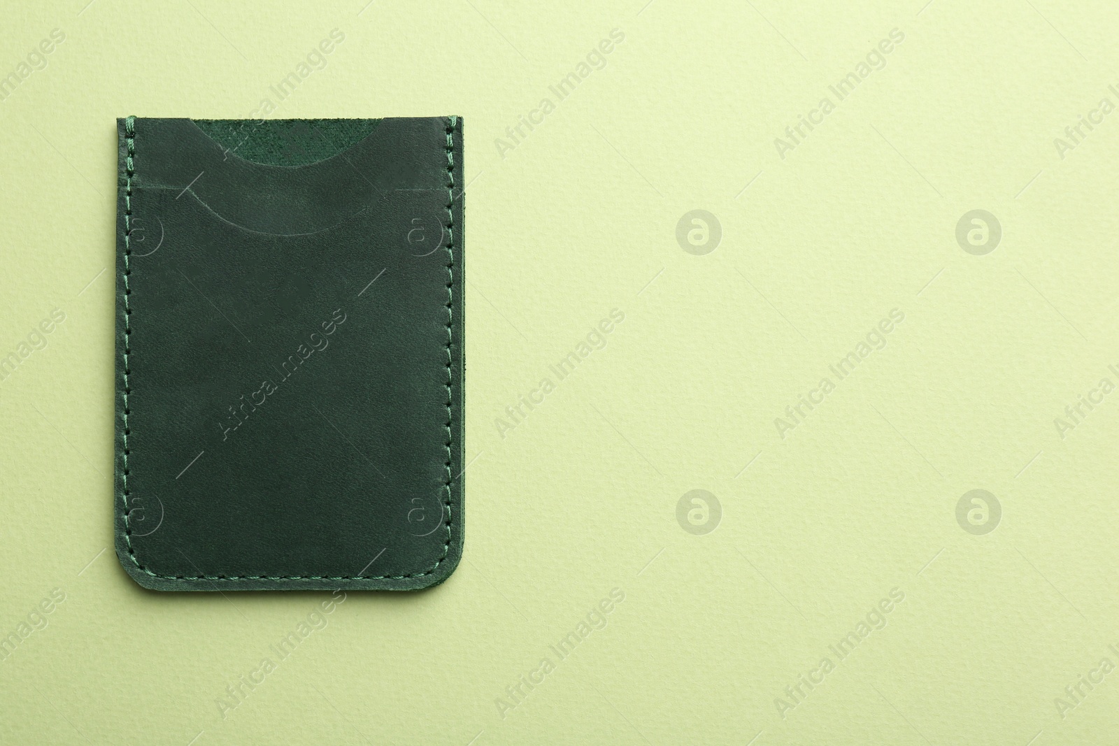 Photo of Empty leather card holder on light green background, top view. Space for text