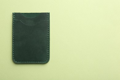 Photo of Empty leather card holder on light green background, top view. Space for text