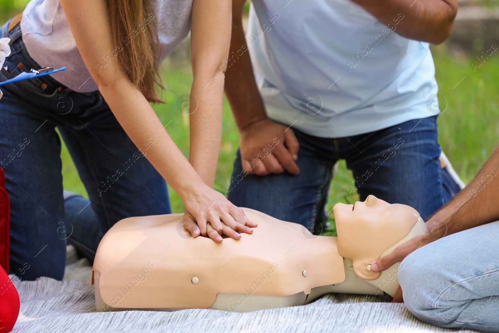 Photo of Woman practicing CPR on mannequin at first aid class outdoors