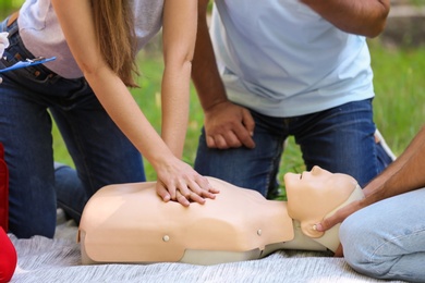 Woman practicing CPR on mannequin at first aid class outdoors