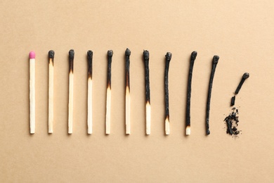 Photo of Row of burnt matches and whole one on color background, flat lay. Human life phases concept