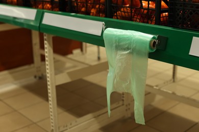 Plastic bags near crates with tangerines in supermarket, space for text