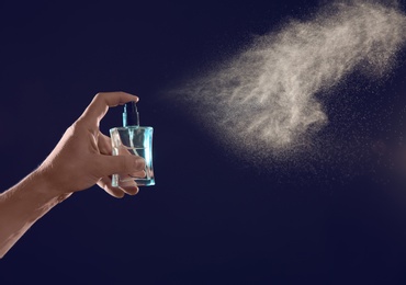 Photo of Young man spraying perfume on black background, closeup