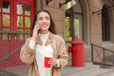 Photo of Young woman talking on mobile phone outdoors