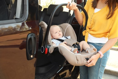 Photo of Mother taking child safety seat with baby out of car