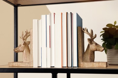 Wooden deer shaped bookends with books and plant on shelf indoors