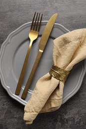 Stylish cutlery, plate and napkin on grey table, top view