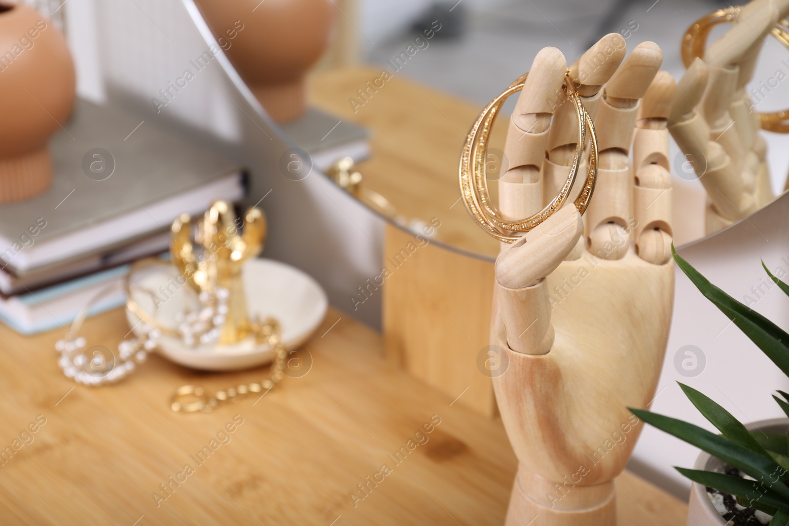 Photo of Decorative hand with earrings on wooden dressing table indoors. Space for text