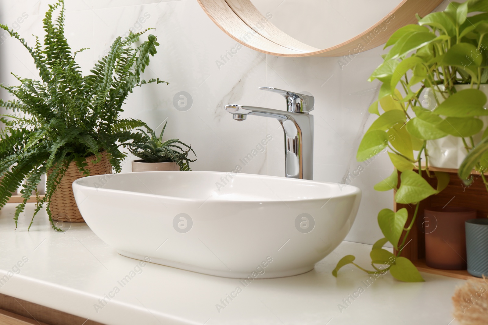 Photo of Bathroom counter with sink and beautiful green houseplants near white marble wall