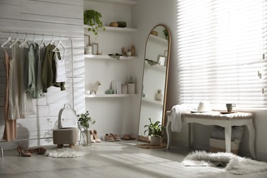 Photo of Rack with different stylish clothes, shoes and decorative elements in dressing room. Interior design