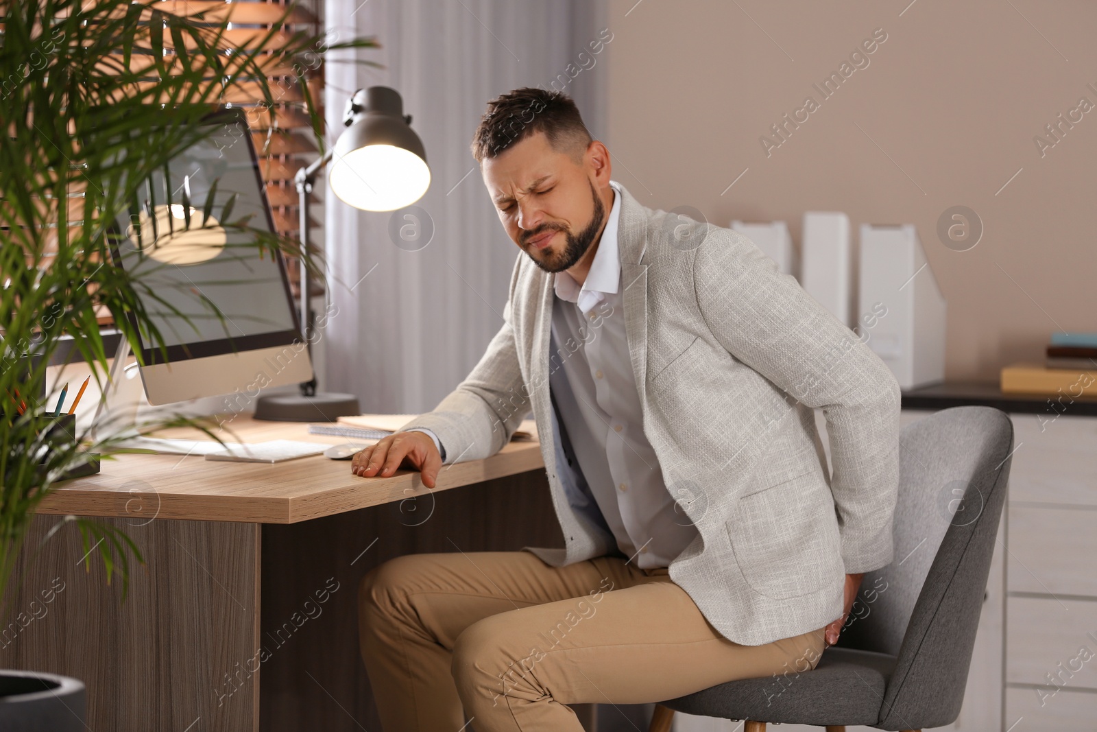 Photo of Man suffering from hemorrhoid at workplace in office