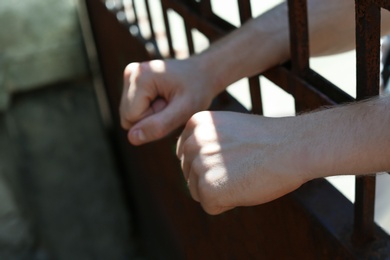 Photo of Man detained in jail outdoors, closeup. Criminal law