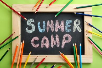 Photo of Text "SUMMER CAMP" on chalkboard and pencils, top view