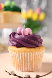 Photo of Tasty Easter cupcake with bright cream on table, closeup