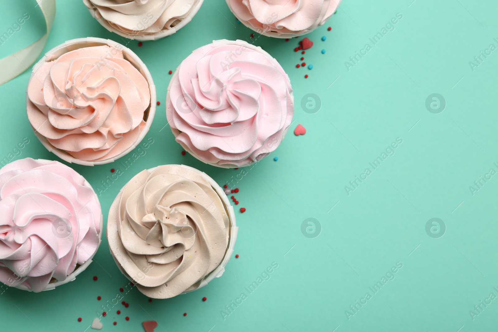 Photo of Delicious birthday cupcakes, ribbon and sprinkles on turquoise background, flat lay. Space for text