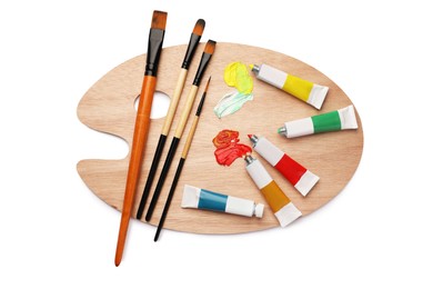 Photo of Wooden palette with oil paints and brushes on white background, top view