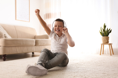 Photo of Little boy listening to music on floor at home