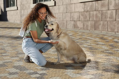 Photo of Young African-American woman and her Golden Retriever dog outdoors