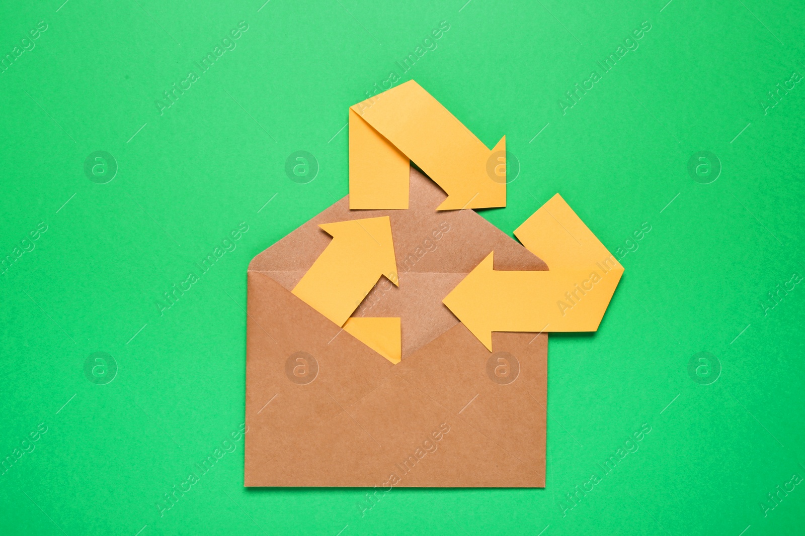 Photo of Open envelope and recycling symbol on green background, top view