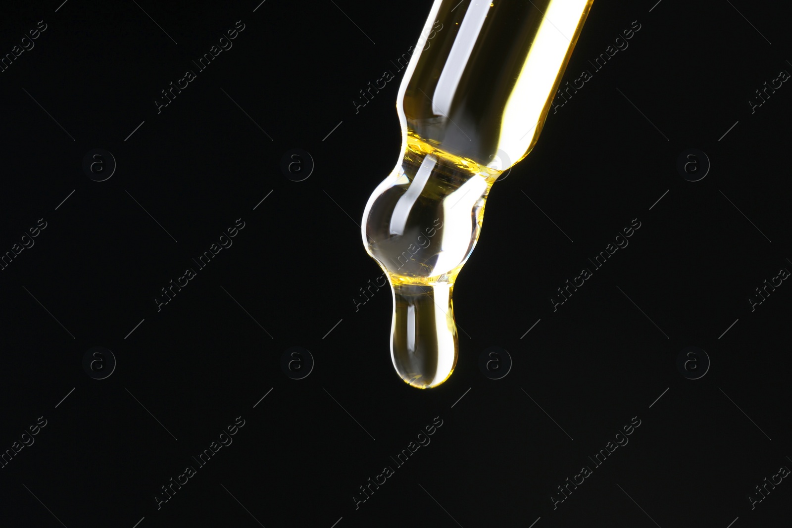 Photo of Dripping tincture from pipette on black background, closeup