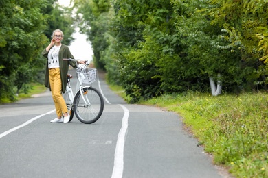 Photo of Beautiful woman in casual outfit with bicycle outdoors. Space for text