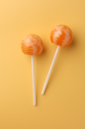 Photo of Tasty lollipops on orange background, flat lay