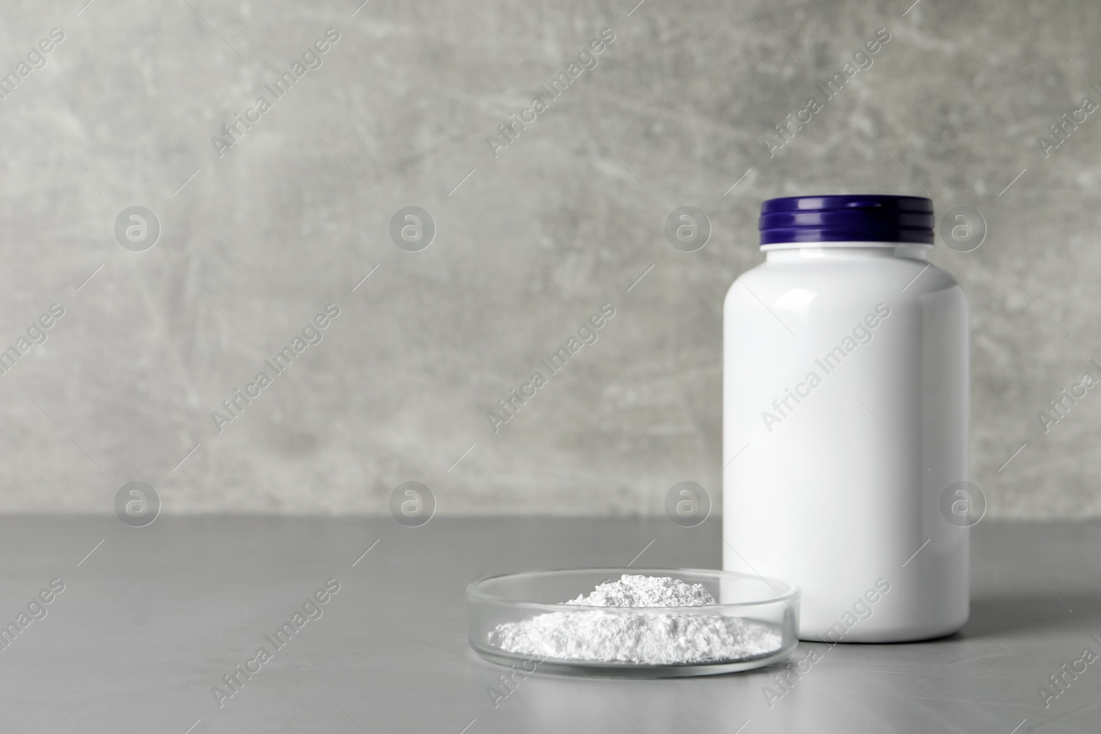 Photo of Jar and petri dish with calcium carbonate powder on grey table. Space for text