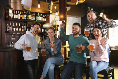 Photo of Group of friends watching football in sport bar