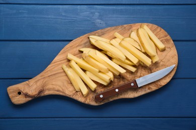 Photo of Cut raw potatoes and knife on blue wooden table, top view. Cooking delicious French fries
