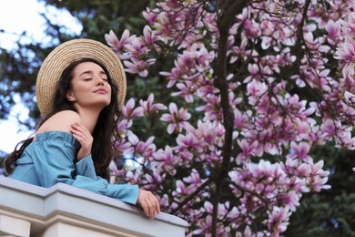 Beautiful woman near blossoming magnolia tree on spring day