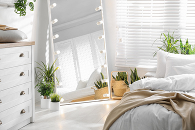 Photo of Stylish mirror with light bulbs in modern bedroom. Interior design