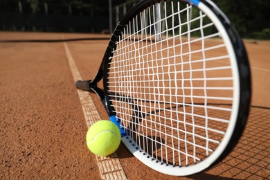 Photo of Tennis ball and racket on clay court, closeup
