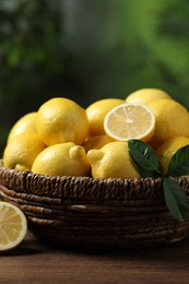 Photo of Fresh lemons in wicker basket on wooden table