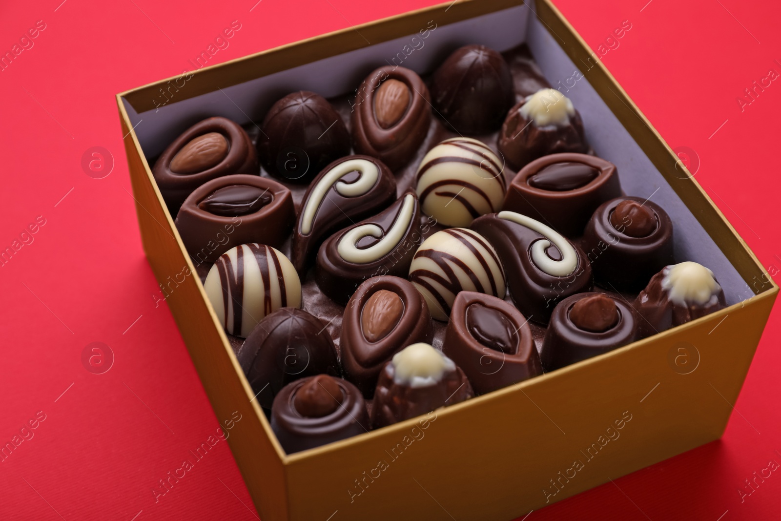 Photo of Box of delicious chocolate candies on red background