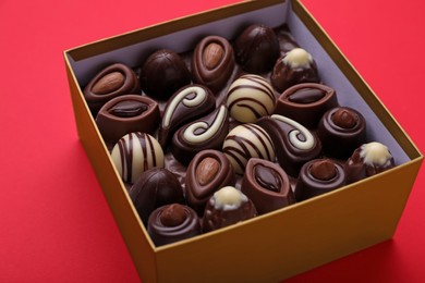 Box of delicious chocolate candies on red background