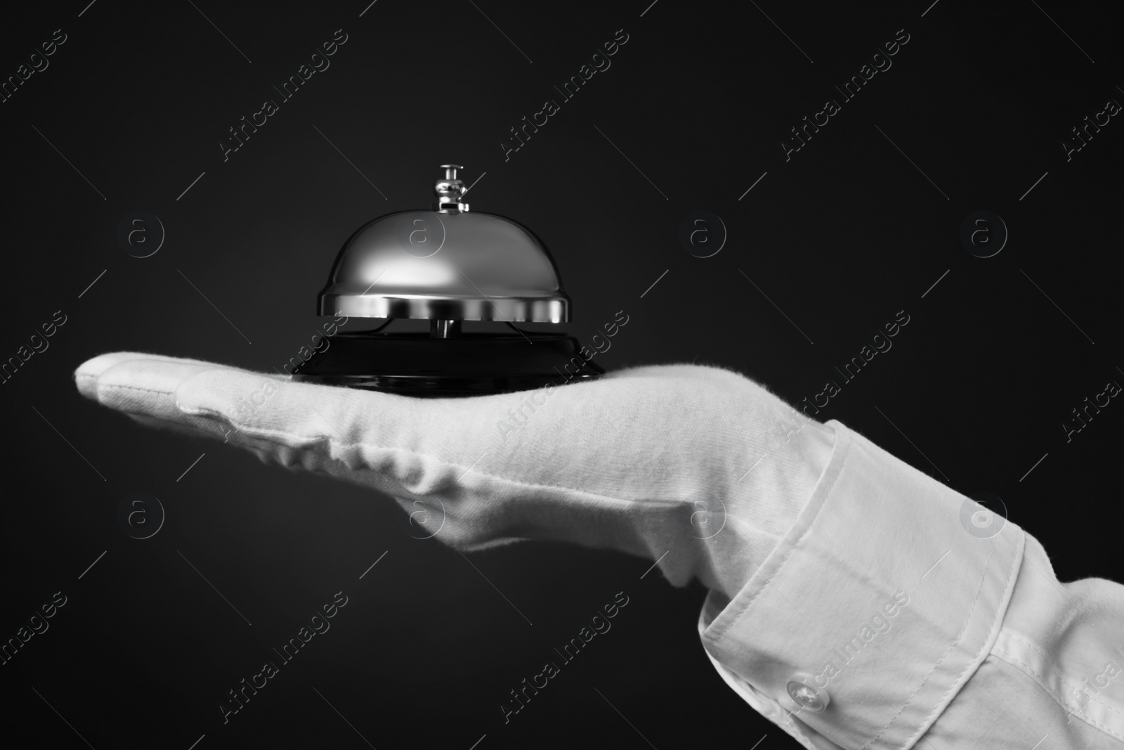 Photo of Butler holding service bell on black background, closeup