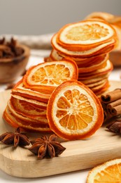 Photo of Dry orange slices, anise stars and cinnamon sticks on wooden board, closeup