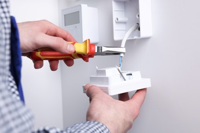 Photo of Professional repairman fixing electric house appliance with pliers indoors, closeup