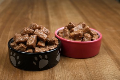 Photo of Wet pet food in feeding bowls on wooden background