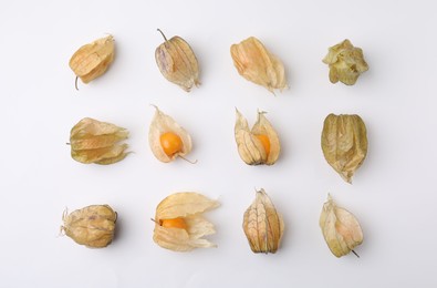 Ripe physalis fruits with calyxes on white background, flat lay